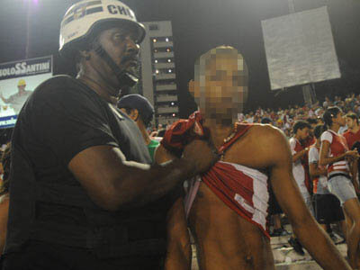Policial militar contendo torcedor dentro do estádio